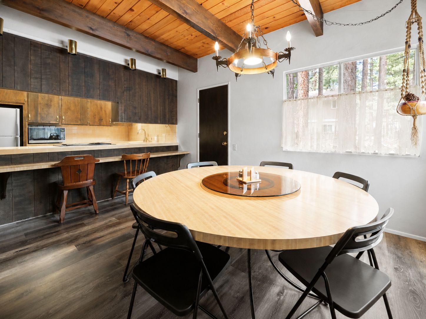 A modern kitchen with dark wood cabinets, a round wooden table, and black chairs.