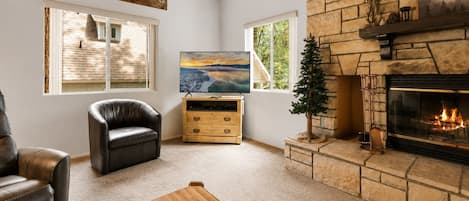A living room with a fireplace, a television, a leather chair, and a wooden coffee table.
