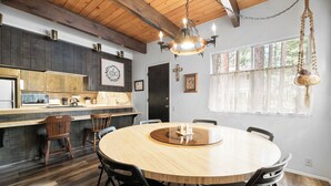 A modern kitchen with dark wood cabinets, a wooden dining table, and black chairs. - Sky Krest (Big Bear Lake)