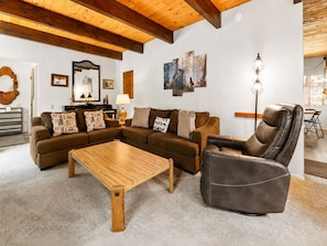A cozy living room with a sectional sofa, a leather armchair, a wooden coffee table, and a floor lamp. - Sky Krest (Big Bear Lake)
