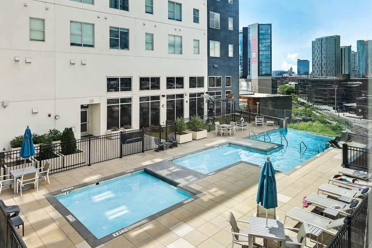 Un espace piscine sur le toit, comprenant deux piscines, des chaises longues et une vue sur le panorama urbain.