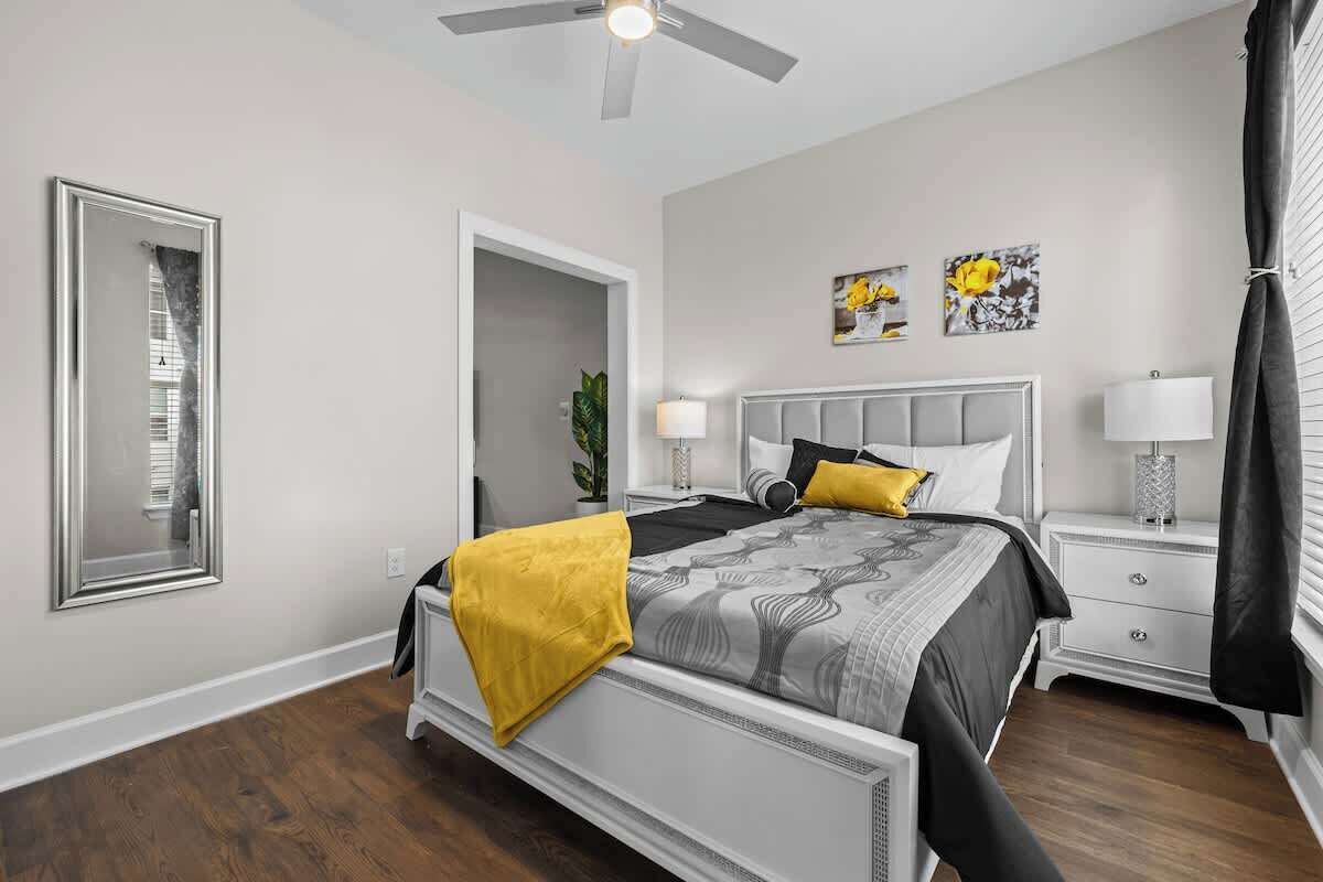 A bedroom with a bed, bedside tables, a ceiling fan, and artwork on the wall.