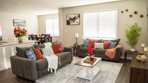 A modern living room with two sofas, a coffee table, and a dining area with a kitchen in the background. - Spacious 4-bedroom house in beautiful Conroe with King Suite (Conroe)