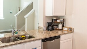 A kitchen with white cabinets, a dishwasher, and a granite countertop. - Spacious 4-bedroom house in beautiful Conroe with King Suite (Conroe)