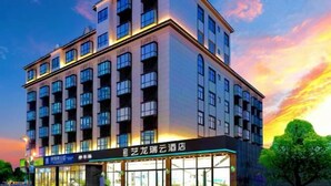 Een hotel met meerdere verdiepingen, met een modern architectonisch ontwerp, met een opvallende ingang met glazen deuren en een bord waarop staat dat het een hotel is.