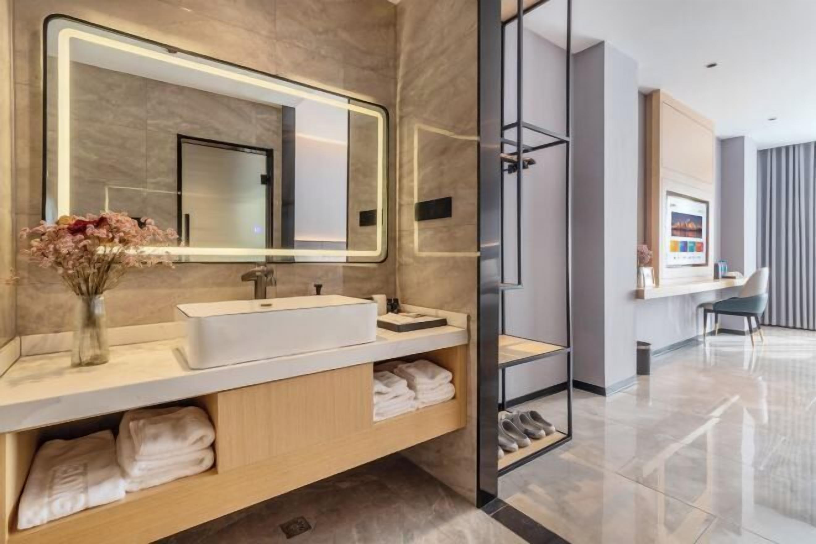 Un baño moderno con un espejo grande, un lavamanos blanco y una cabina de ducha de vidrio.