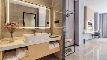 Un baño moderno con un espejo grande, un lavamanos blanco y una cabina de ducha de vidrio.