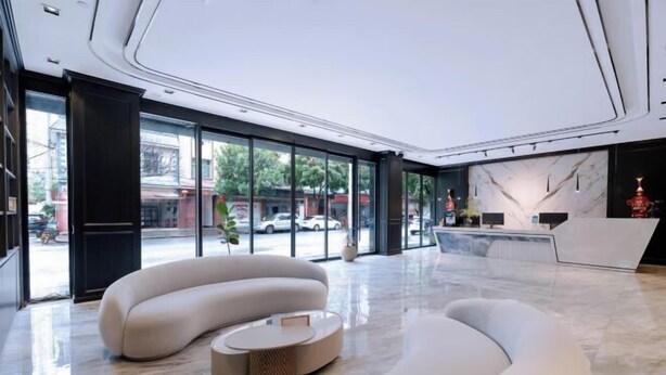 Een moderne lobby met een gebogen bank, een receptiebalie en een groot raam met uitzicht op de straat.