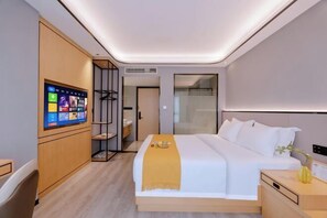 A modern hotel room with a large bed, a bedside table, a TV mounted on the wall, and a wardrobe.