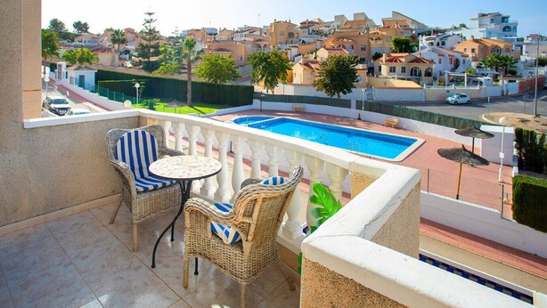 Ein Balkon mit Korbmöbeln, ein Pool und Blick auf eine Wohngegend.