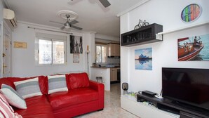 Ein Wohnzimmer mit einem roten Ledersofa, einem Flachbildfernseher und einem Deckenventilator.