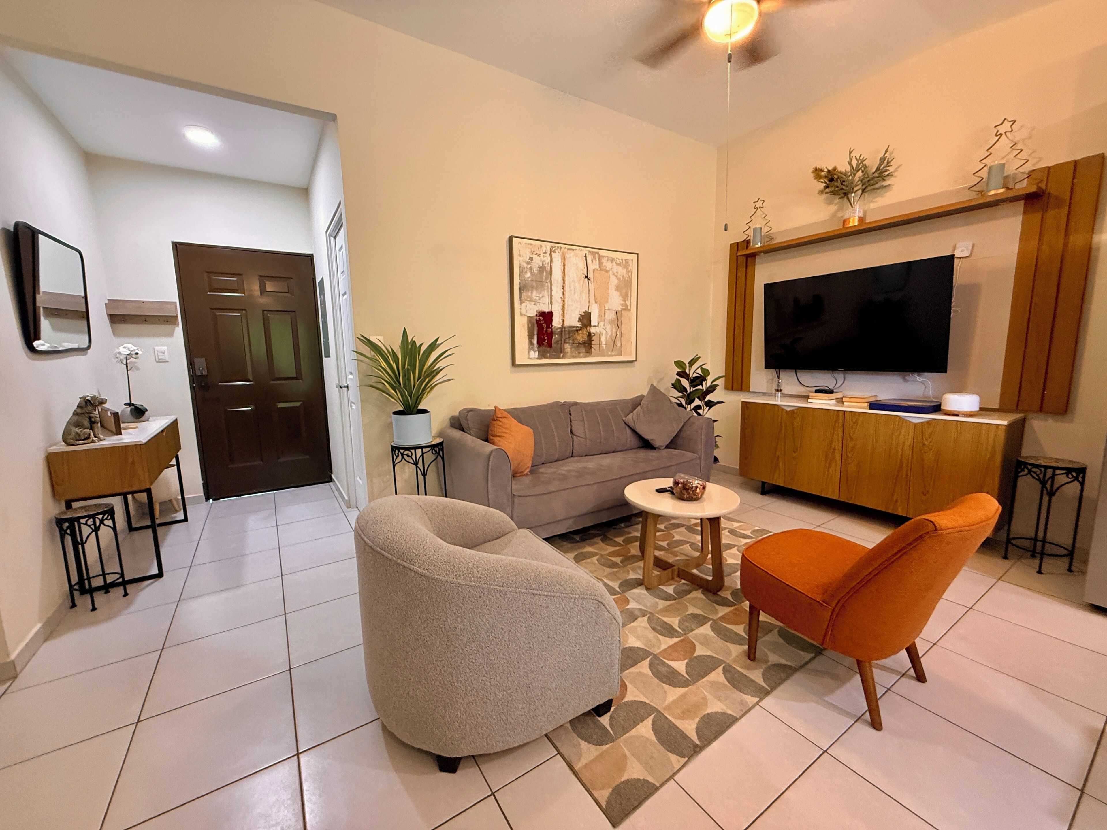A living room with a sofa, armchair, coffee table, and a television.
