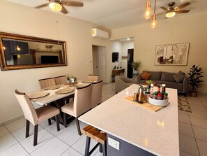 A modern kitchen with a central island, dining area with chairs, ceiling fans, and a living area with a couch. - Beautiful house in the most exclusive area of ​​San Miguel (San Miguel)