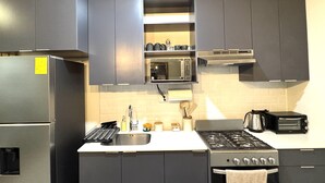 A modern kitchen with grey cabinets, a stainless steel refrigerator, a microwave, a stove, and a toaster. - Beautiful house in the most exclusive area of ​​San Miguel (San Miguel)