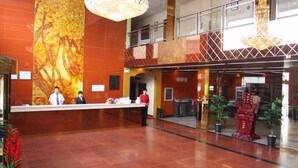 Un vestíbulo de hotel con una recepción, un mural grande y un elemento decorativo rojo.