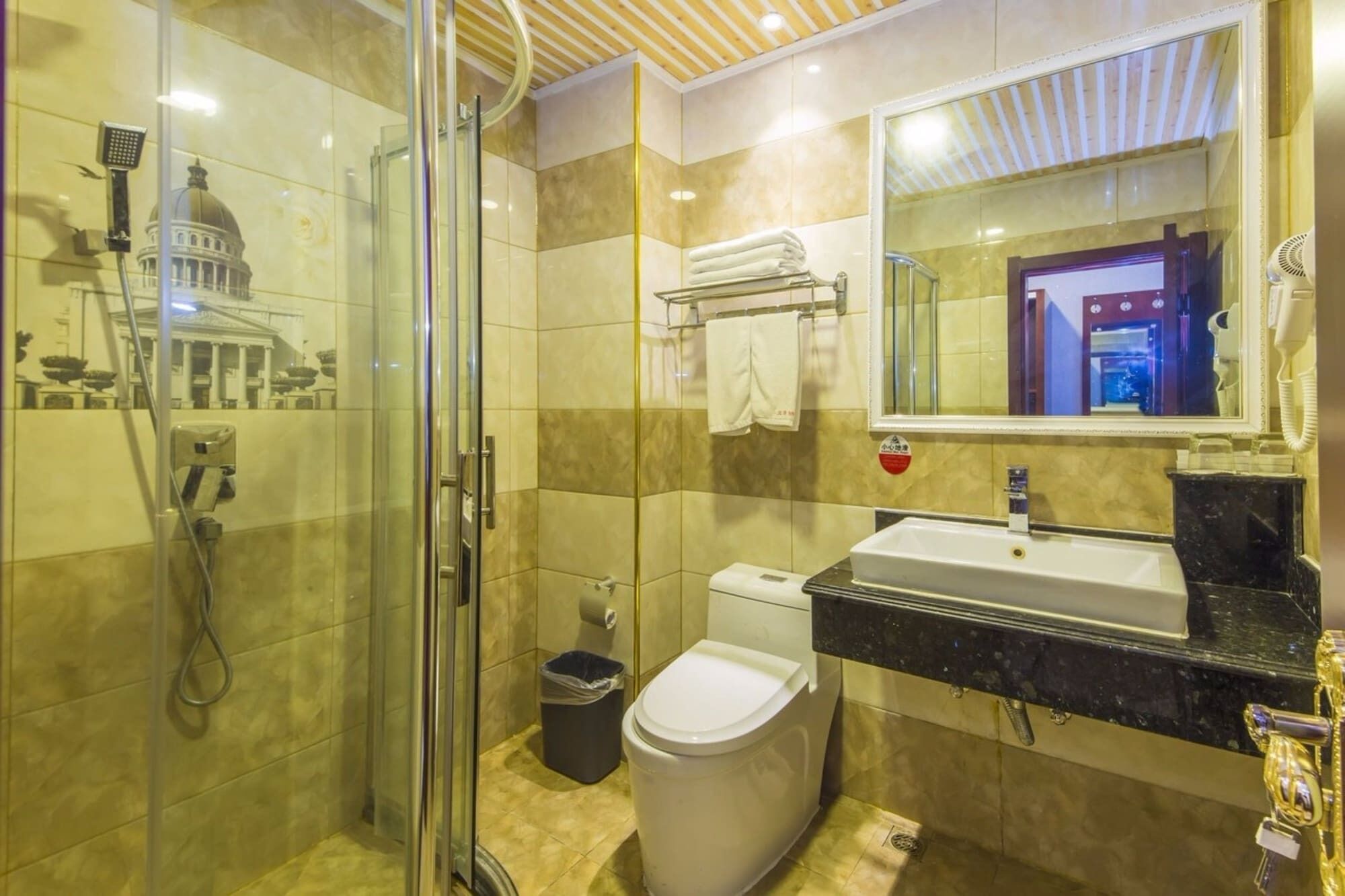 A bathroom with a glass-enclosed shower, a toilet, and a sink with a marble countertop.