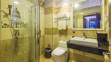 A bathroom with a glass-enclosed shower, a toilet, and a sink with a marble countertop.
