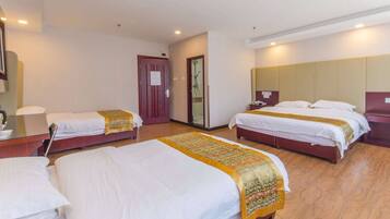 A hotel room with two single beds, a wooden floor, a large mirror, and a door leading to a bathroom.