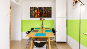 Un comedor moderno con una mesa de madera, sillas negras y una decoración en tonos verde y blanco.