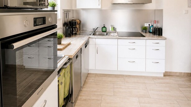 Una cocina moderna con armarios blancos, horno empotrado, lavamanos y estufa.