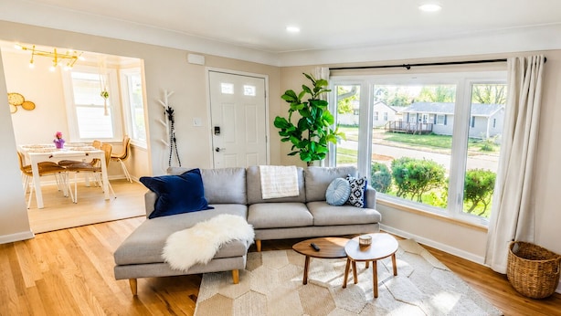 A modern living room with a grey sofa, a coffee table, and a view of the outdoors.