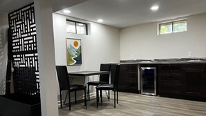 A modern kitchen with a dining area, featuring a black and white patterned partition, a dining table with chairs, and a built-in oven.