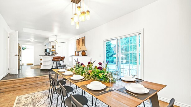 A spacious dining area with a long wooden table set for six, surrounded by black chairs. A large window provides a view of the outdoors. - Luxury Winery Country Retreat: Heated Pool, Hot Tub and Games (Niagara-on-the-Lake)