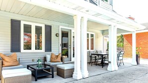 A covered patio with outdoor furniture, including a sofa, chairs, and a table. - Luxury Winery Country Retreat: Heated Pool, Hot Tub and Games (Niagara-on-the-Lake)