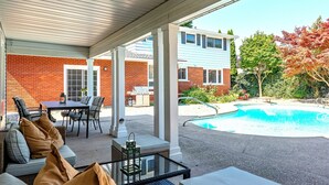 A covered patio area with a pool, outdoor furniture, and a brick wall. - Luxury Winery Country Retreat: Heated Pool, Hot Tub and Games (Niagara-on-the-Lake)