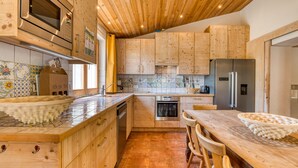 A kitchen with wooden cabinets, a stainless steel refrigerator, a microwave, and a tiled backsplash. - Orange Riverside House with Shared Pool (Aspiran)