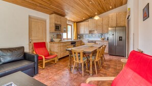 A kitchen with wooden cabinets, a dining table, and chairs. - Orange Riverside House with Shared Pool (Aspiran)