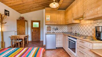 Una cocina con armarios de madera, salpicadero de azulejos, un refrigerador, una estufa y una zona de comedor con mesa y sillas.