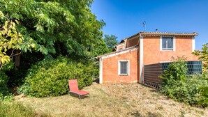 Een huis met een rode stoel in de tuin, omringd door groen.