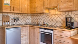 Een keuken met houten kastjes, een vaatwasser, een oven en een koffiezetapparaat.