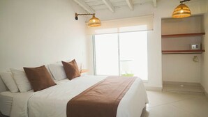 A bedroom with a bed, pillows, a bedside table, a lamp, a window, and a door. - Cartagena Económica con Estilo y Comfot (Cartagena)