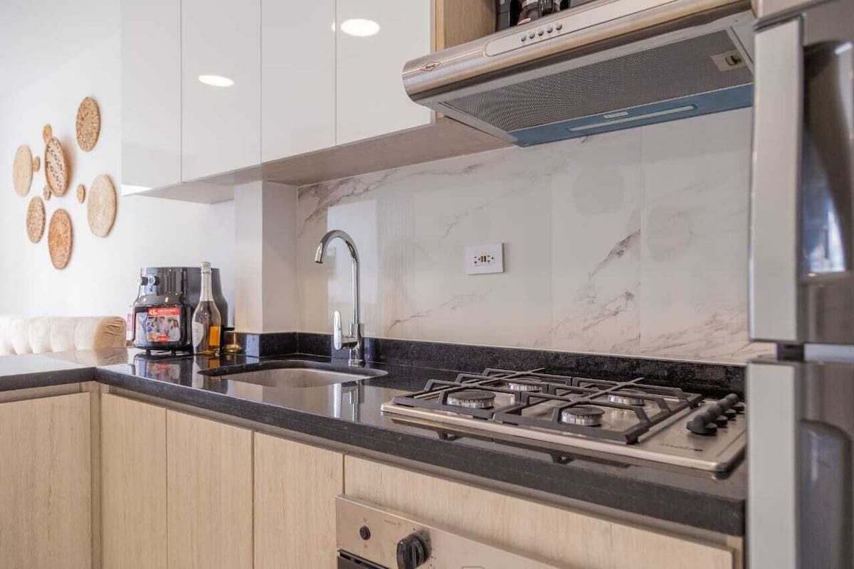 A modern kitchen with a gas stove, stainless steel appliances, and a marble backsplash.