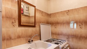 Un baño con lavabo, espejo y estufa a gas.