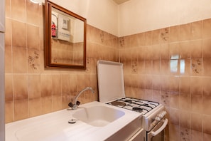 Ein Badezimmer mit Waschbecken, Spiegel und Gasherd.