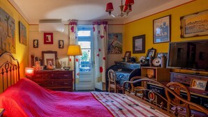 Un dormitorio con cama, cómoda, televisor y puerta que da a un balcón.