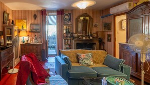 Una sala de estar acogedora con un sofá, una chimenea y un ventilador.