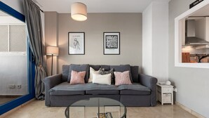 A modern living room with a grey sofa, a glass coffee table, and two framed artworks on the wall. - Apartment 'Kym' with Mountain View, Wi-Fi and Air Conditioning (Duquesa)
