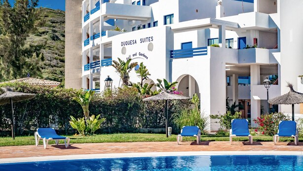 A modern hotel with a pool area, outdoor seating, and a sign indicating 'Duquesa Suites.' - Apartment 'Kym' with Mountain View, Wi-Fi and Air Conditioning (Duquesa)