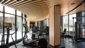 Une salle de sport moderne équipée de tapis de course, de vélos elliptiques et de matériel de musculation.