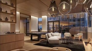 Un intérieur moderne avec une table de billard, un coin salon et de grandes fenêtres offrant une vue dégagée.