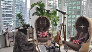 Un salon moderne doté de grandes fenêtres, d’un télescope et de deux fauteuils ornés de drapeaux britanniques.