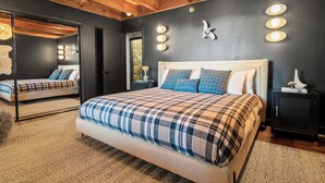 A bedroom with a large bed, a mirror, and a wall-mounted light fixture. - Ski View Chalet (Big Bear Lake)