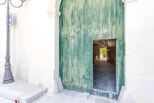 Una puerta verde con un picaporte de metal, una pared blanca y una farola.