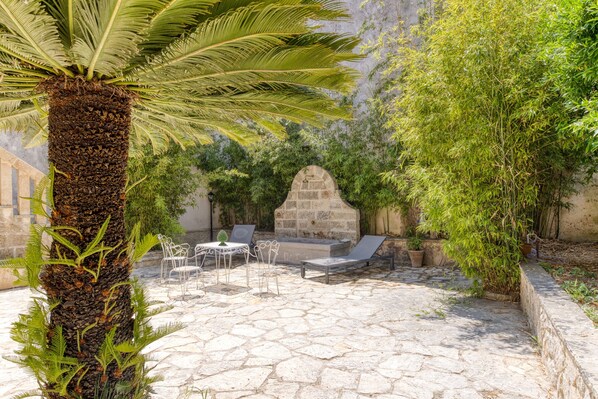 A patio with stone flooring, a palm tree, and outdoor furniture.