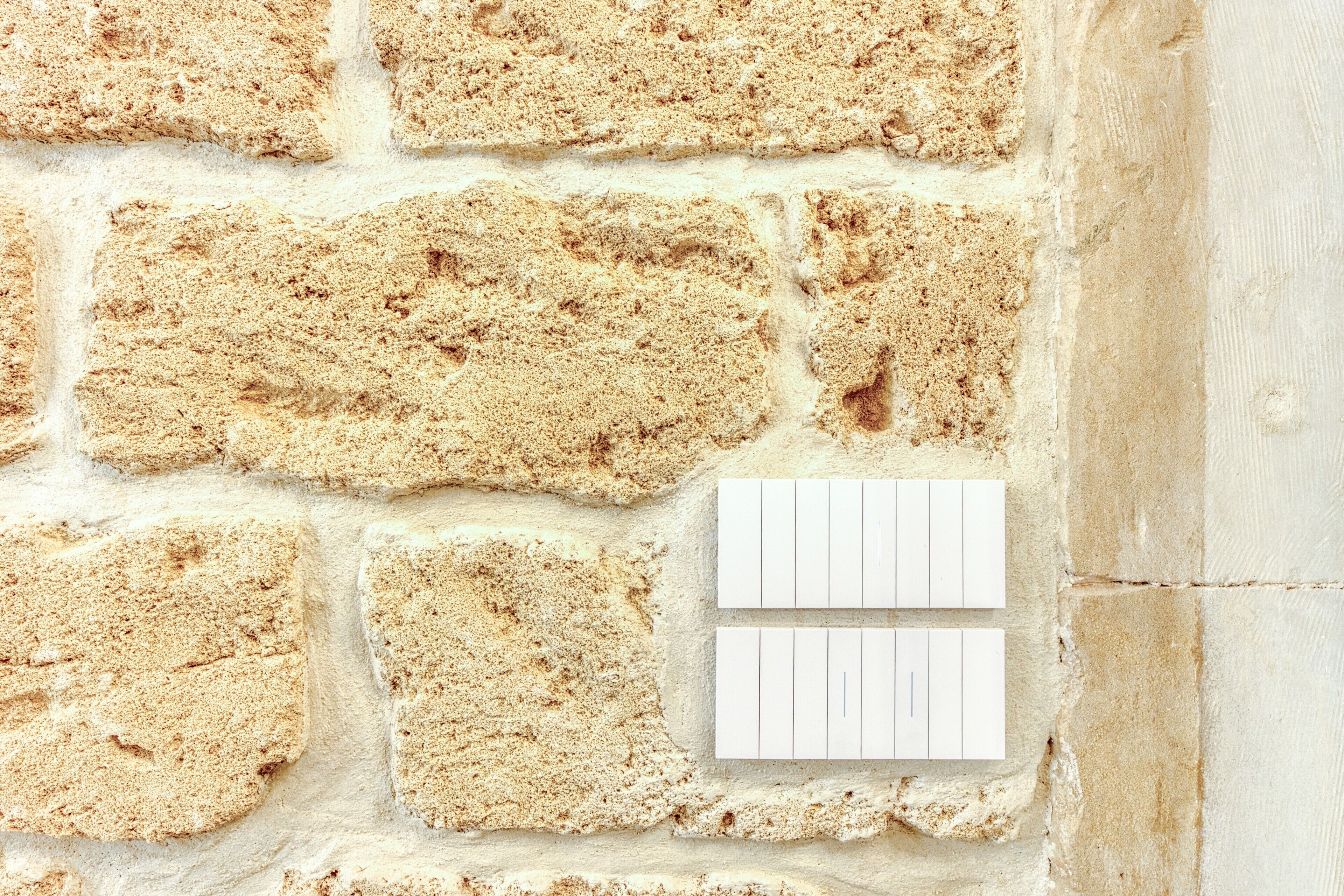 A textured brick wall with two blank white cards attached.
