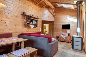 A wooden cabin interior with a sofa, table, and a fireplace.